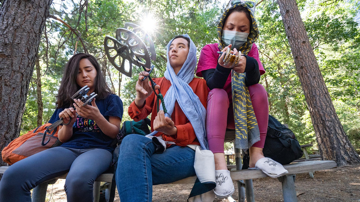 Mina Bakhshi, Haniya Tavasoli and Sughra Yazdani check out a range of cams during a climbing ranger presentation about the evolution of climbing gear and the tools needed to climb in Yosemite National Park, California.